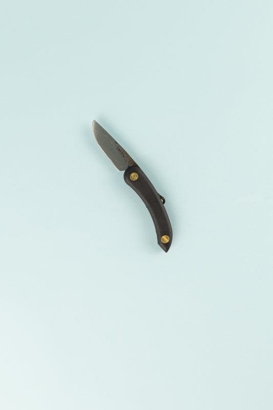 Peasant Knife Mini - Black displayed against a light blue background, showcasing its handcrafted design and steel blade.