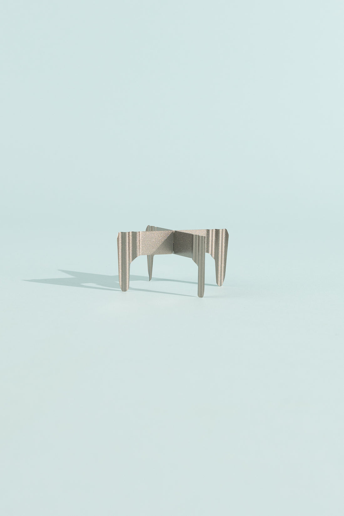 Evernew T0.3 TriveTi modern design table with unique striped legs on a light blue background.