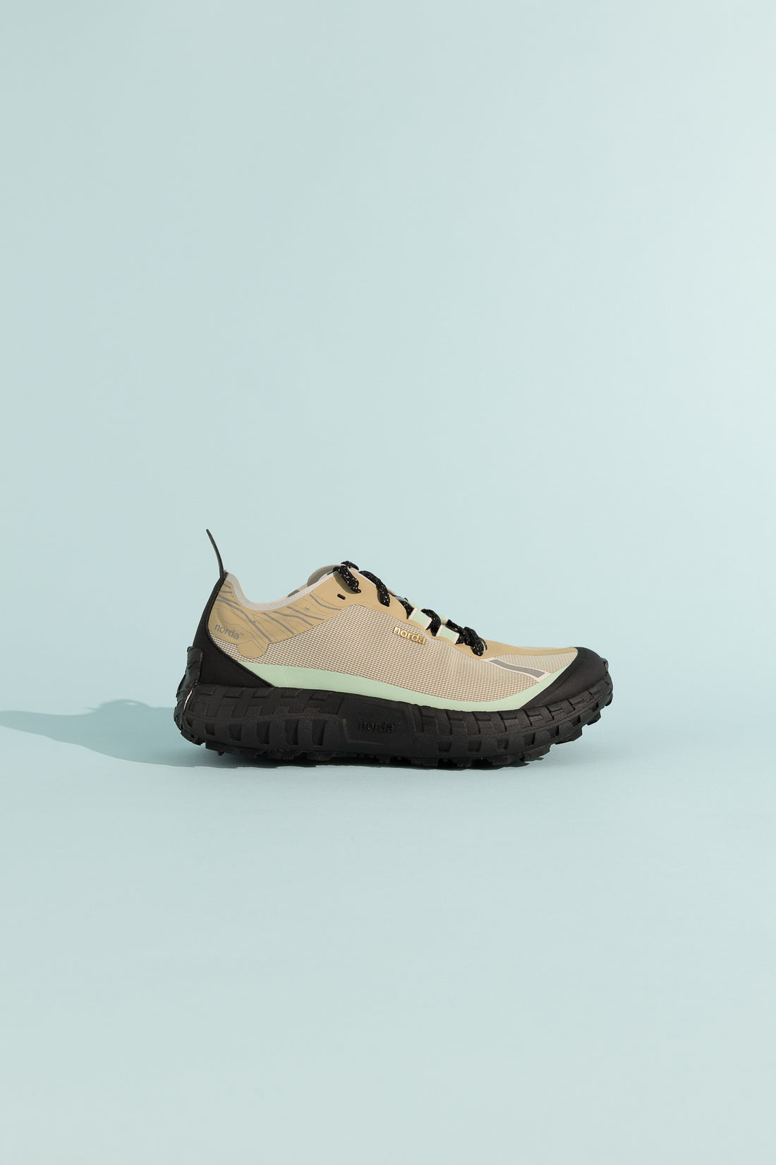 001A - Astral shoe in beige with black sole on light blue background.