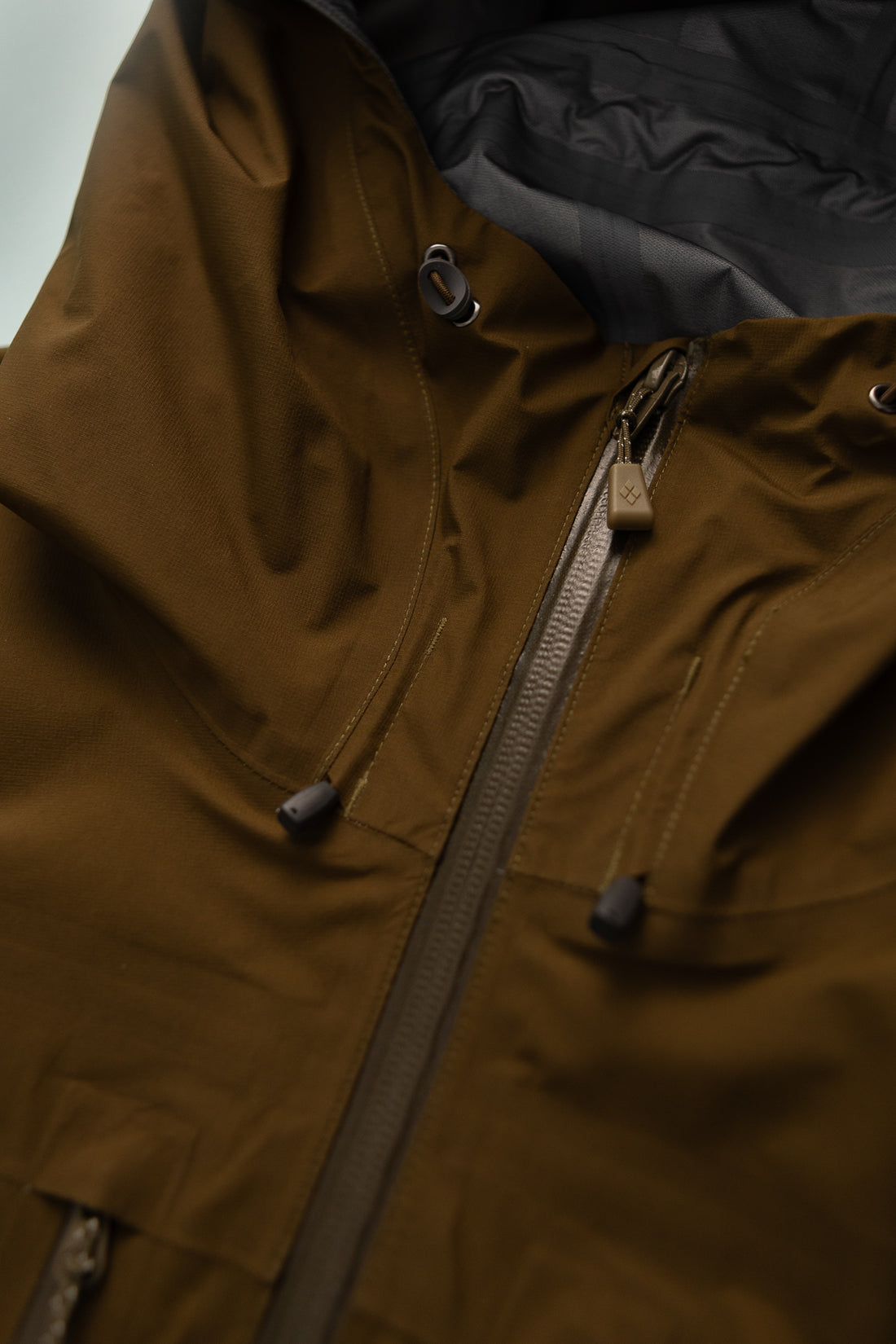 US Men's Tempest Jacket in khaki detail view highlighting the zipper and hood features.