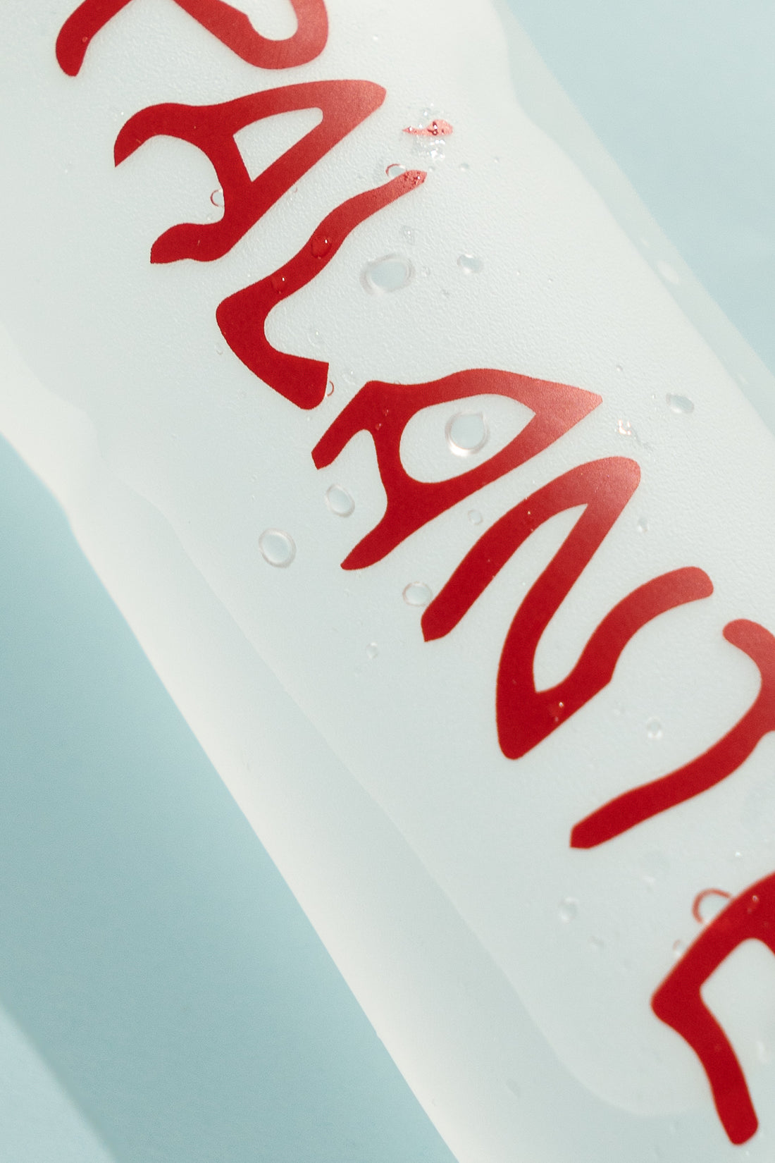 Floppy Water Bottle with red lettering and water droplets, showcasing a reusable and collapsible design.