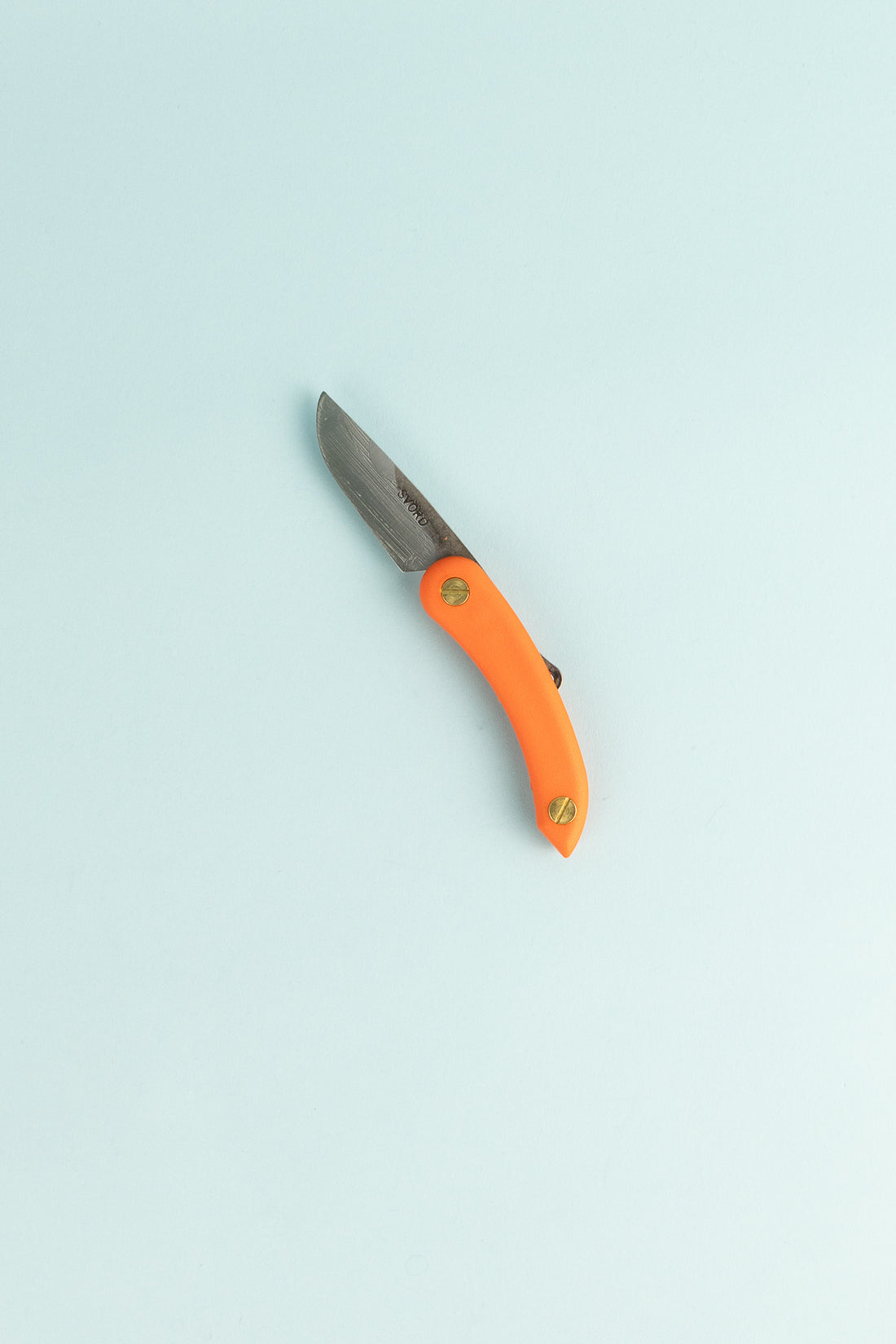 Peasant Knife Mini with an orange handle and carbon steel blade resting on a light background.