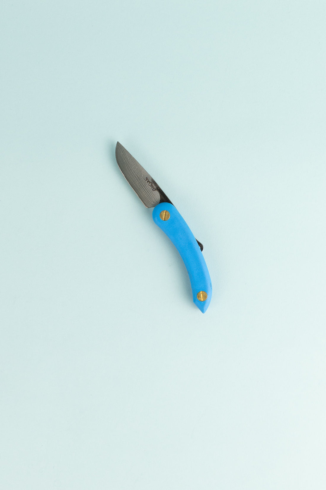Peasant Knife Mini in blue with a carbon steel blade lying on a light background.