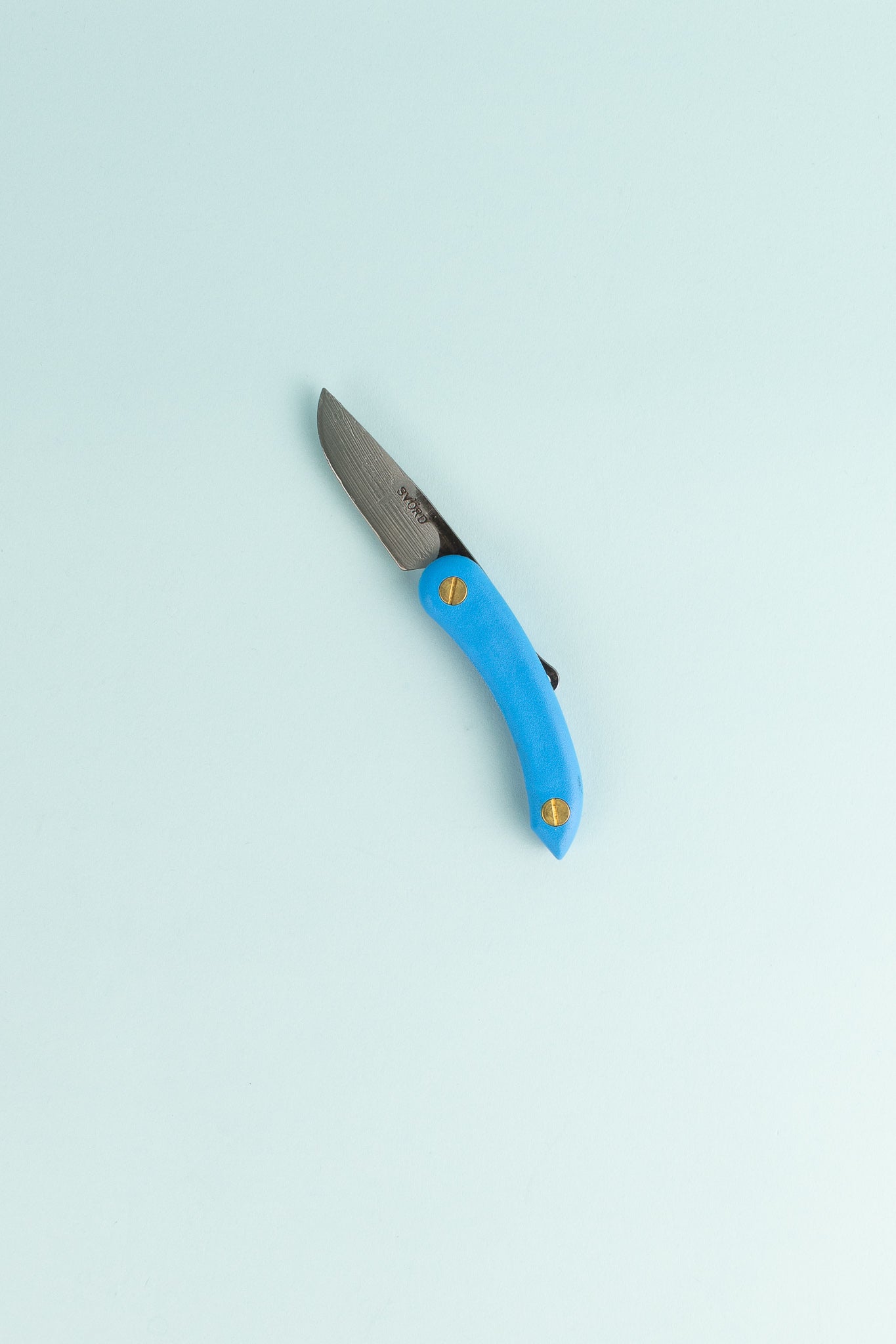Peasant Knife Mini in blue with a carbon steel blade lying on a light background.