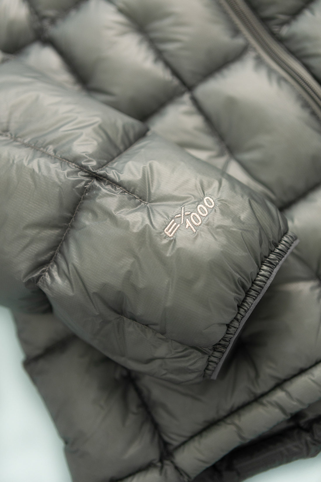 US Men's Plasma 1000 Alpine Down Parka close-up detail of light gray material and 1000 fill down.