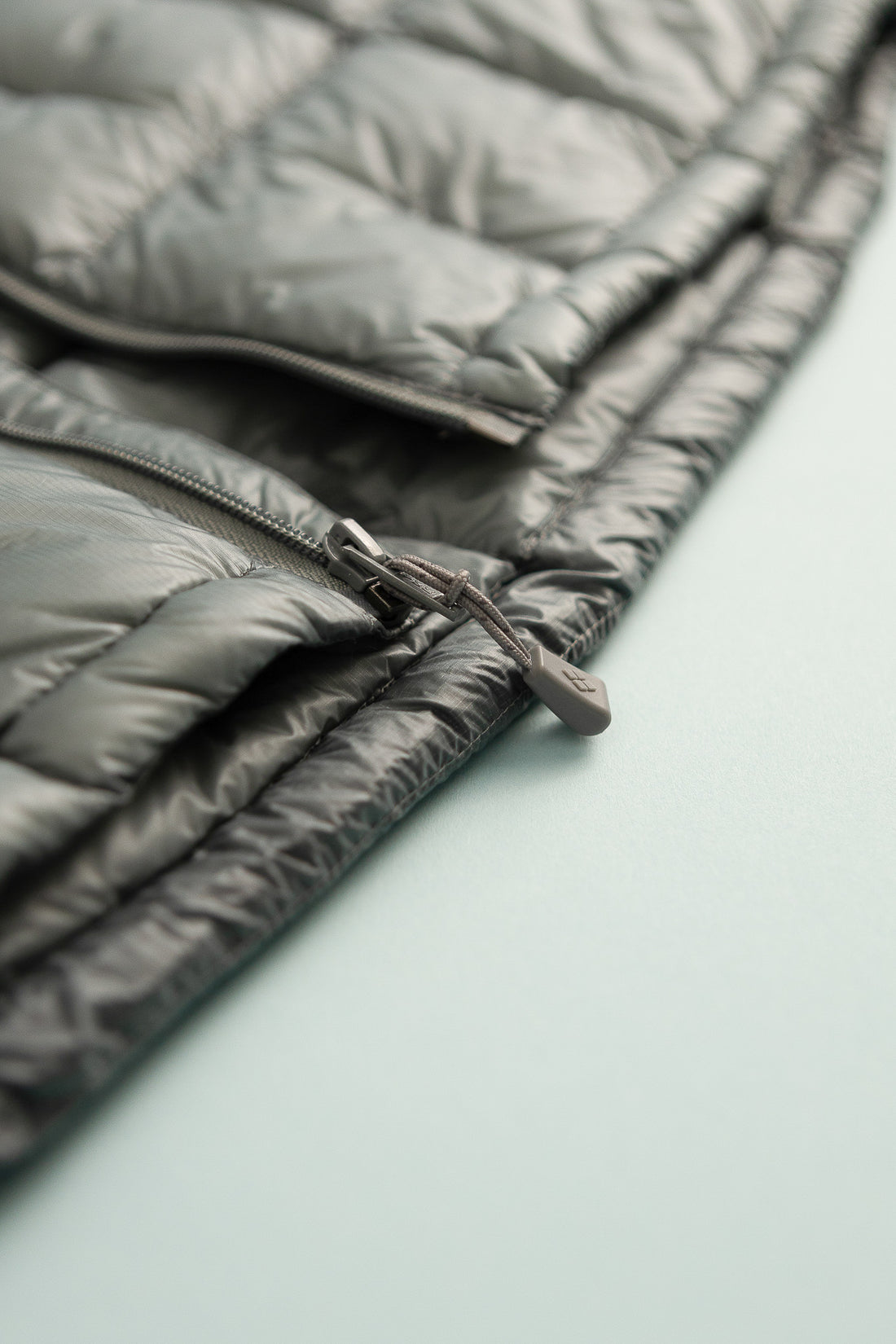 US Men's Plasma 1000 Alpine Down Parka zip detail in light gray fabric.