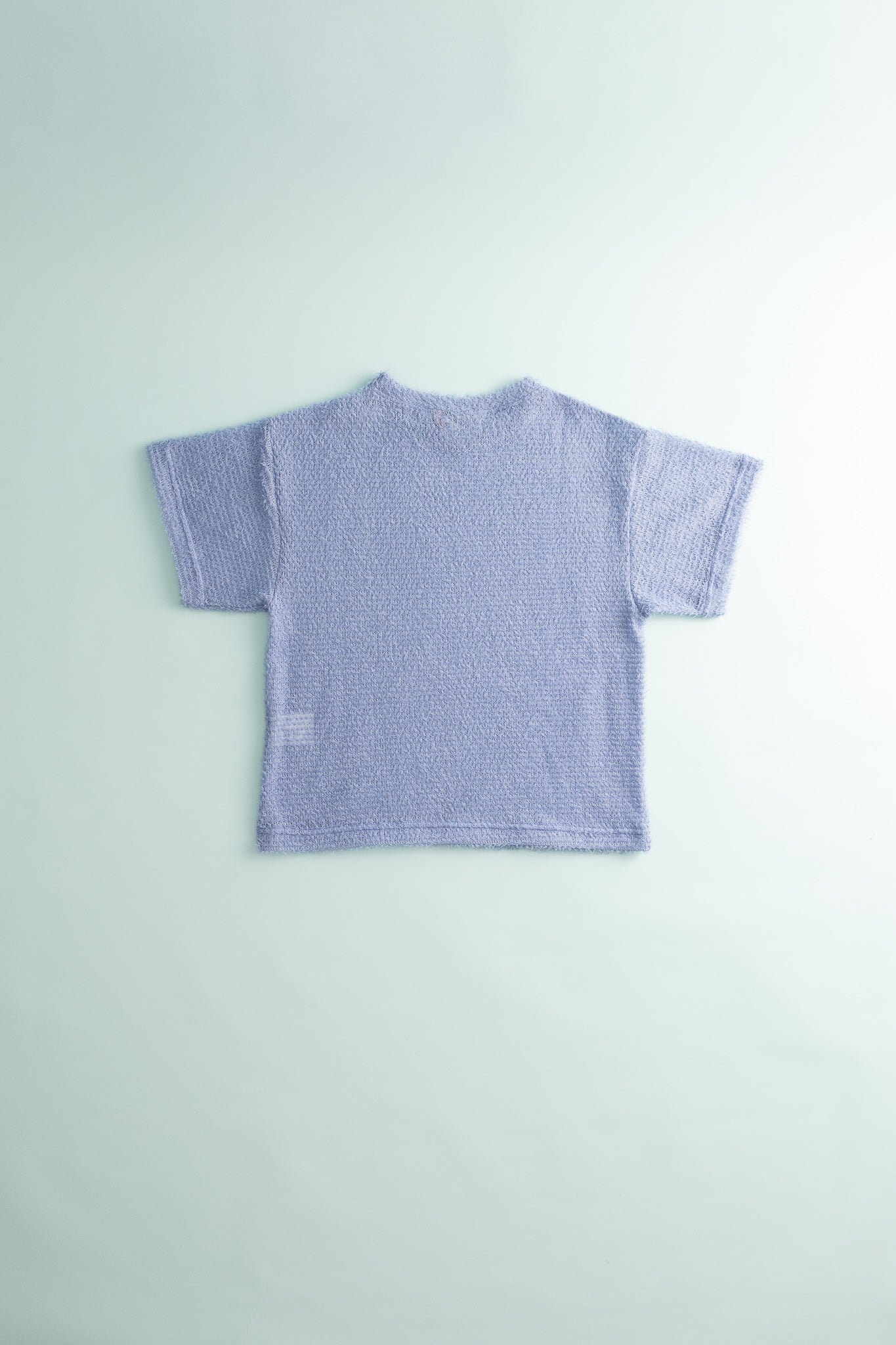 Back view of Shag Tee v2.0 in light purple color, showcasing its ultralight and compressible design.