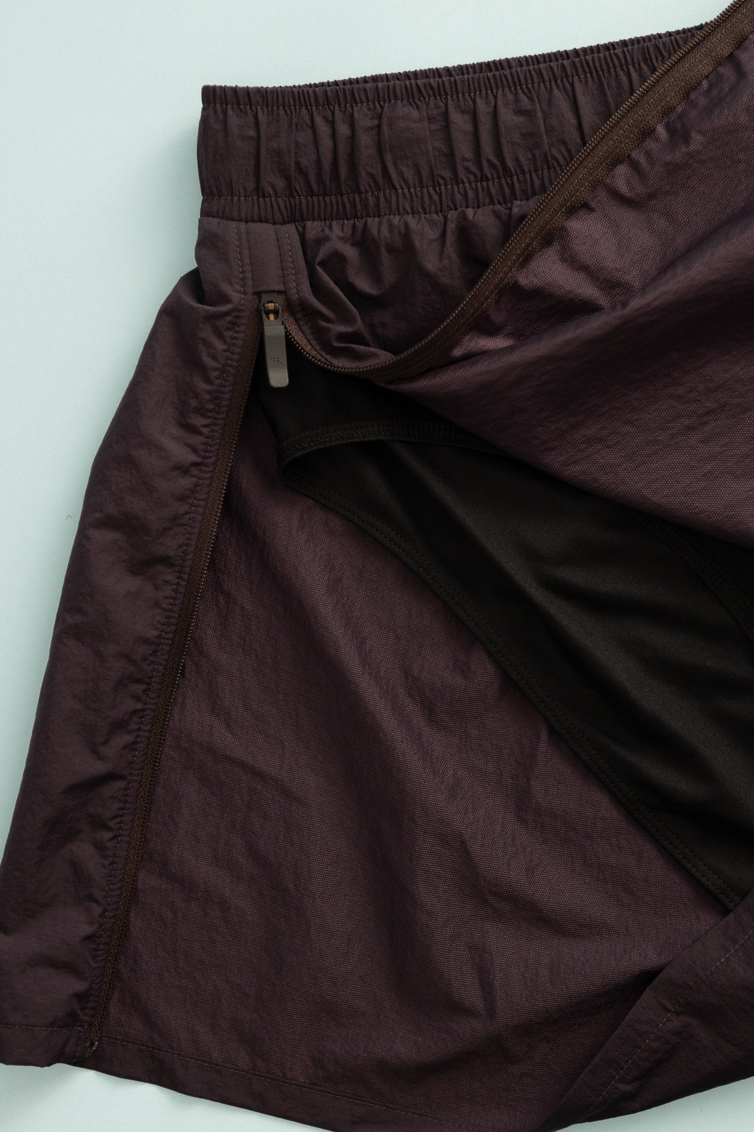 Close-up view of District Vision Women's Ultralight Nylon Zippered Shorts in Nightshade featuring deep split zippers.