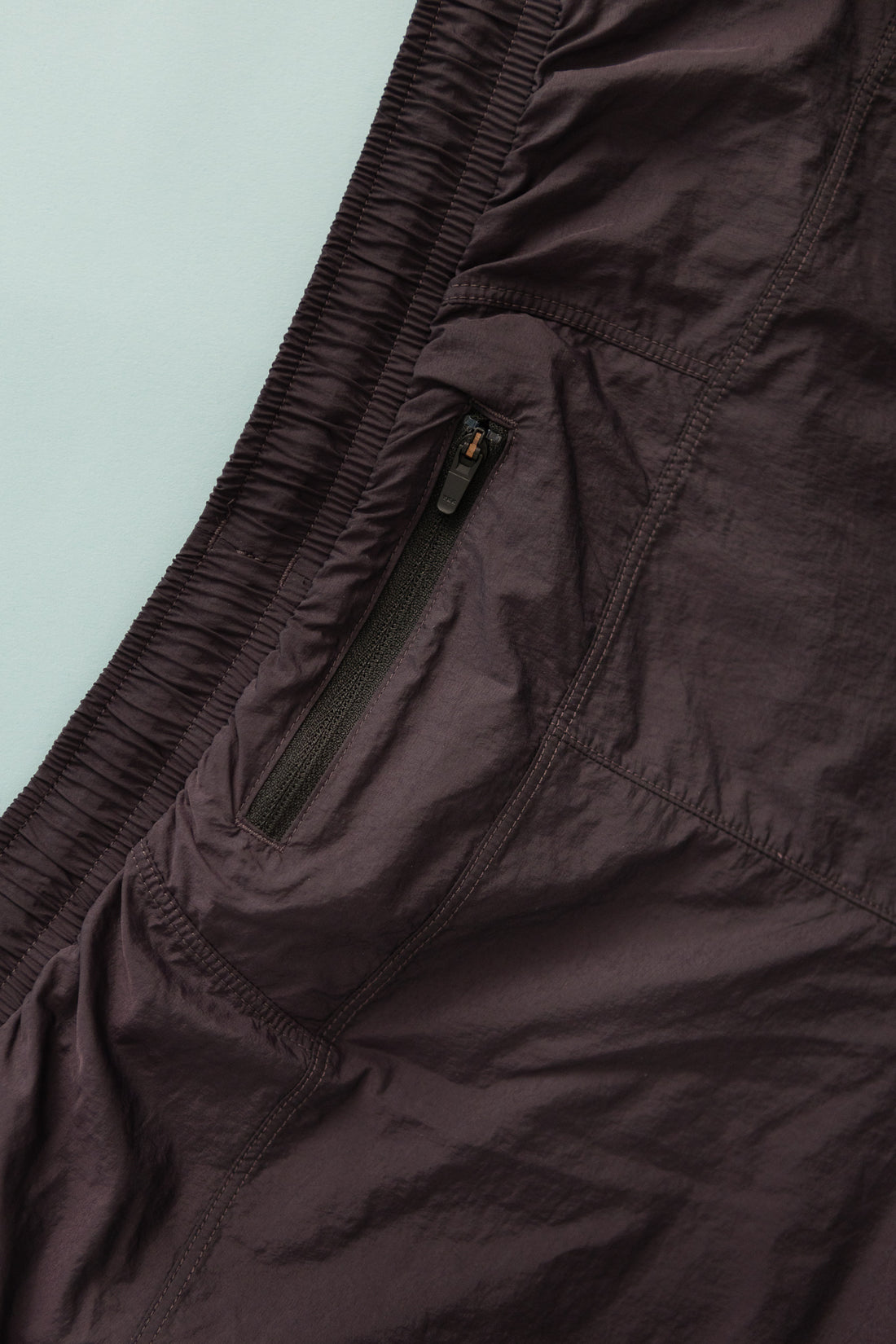 Detail of the District Vision Women's Ultralight Nylon Zippered Shorts showing side zipper pocket in Nightshade color.