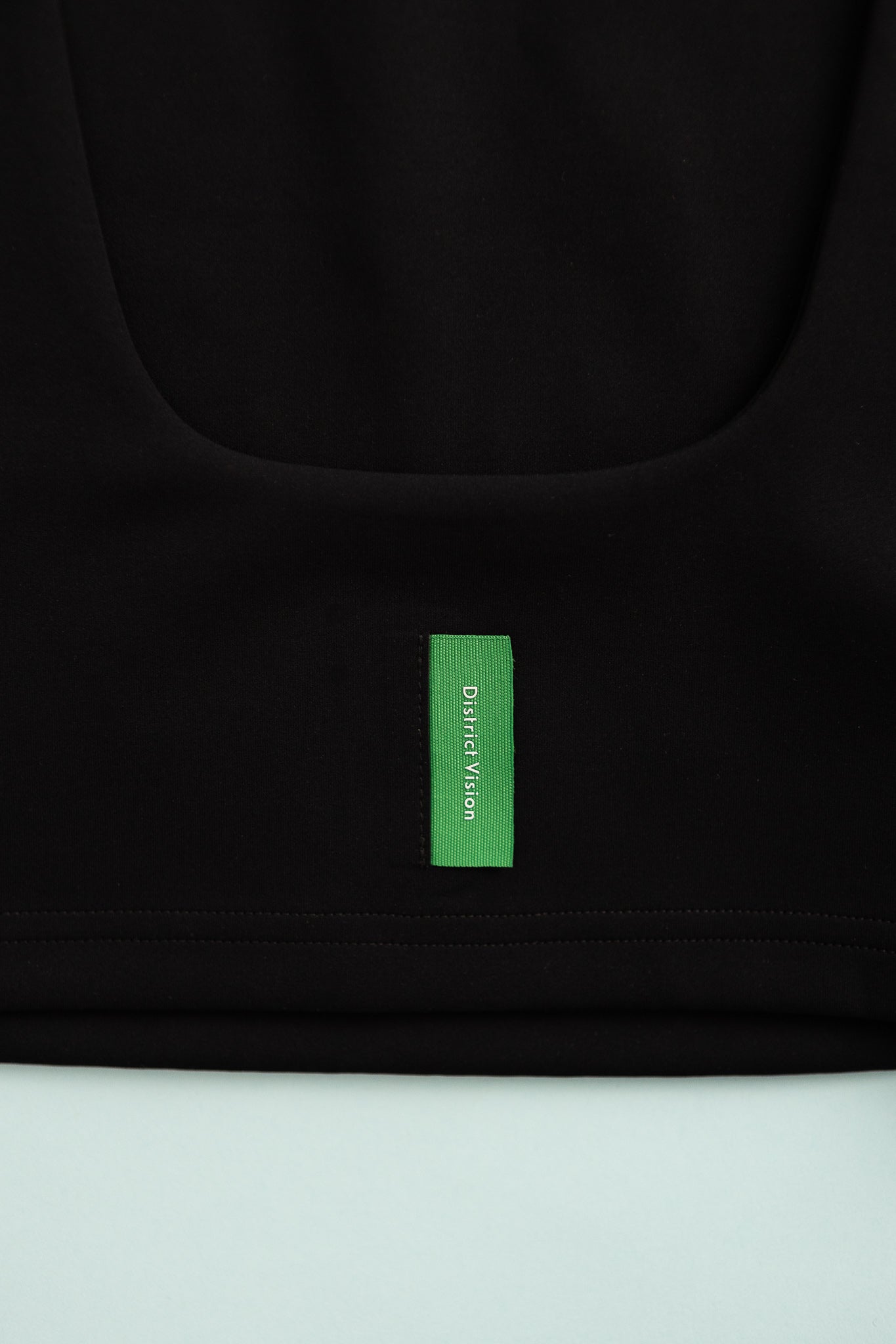 Close-up of District Vision Womens High Neck Interlock Bra label on black fabric.