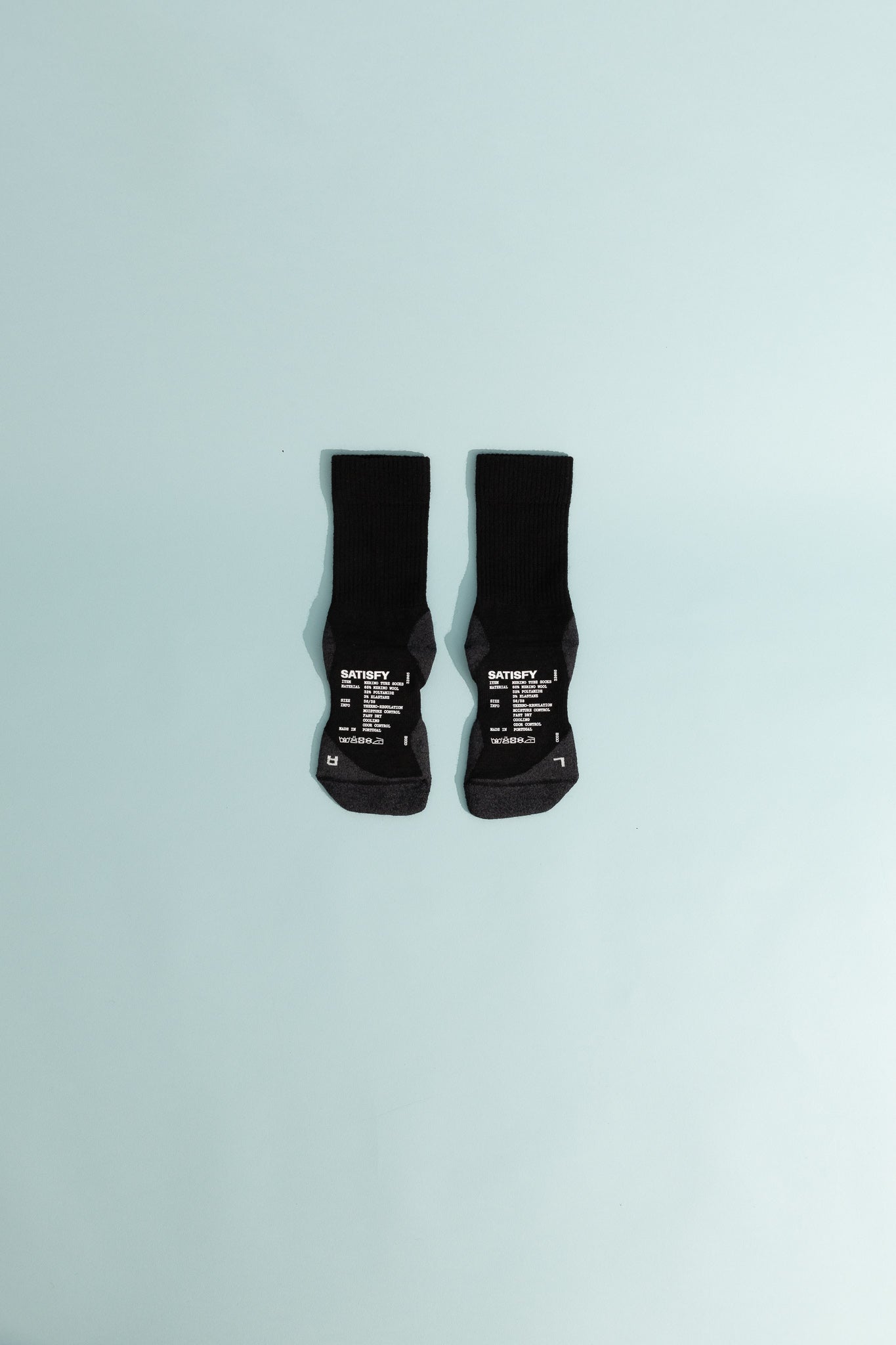 Merino Nylon Tube Socks - Black displayed on a light blue background, showcasing their cushioning and support features.