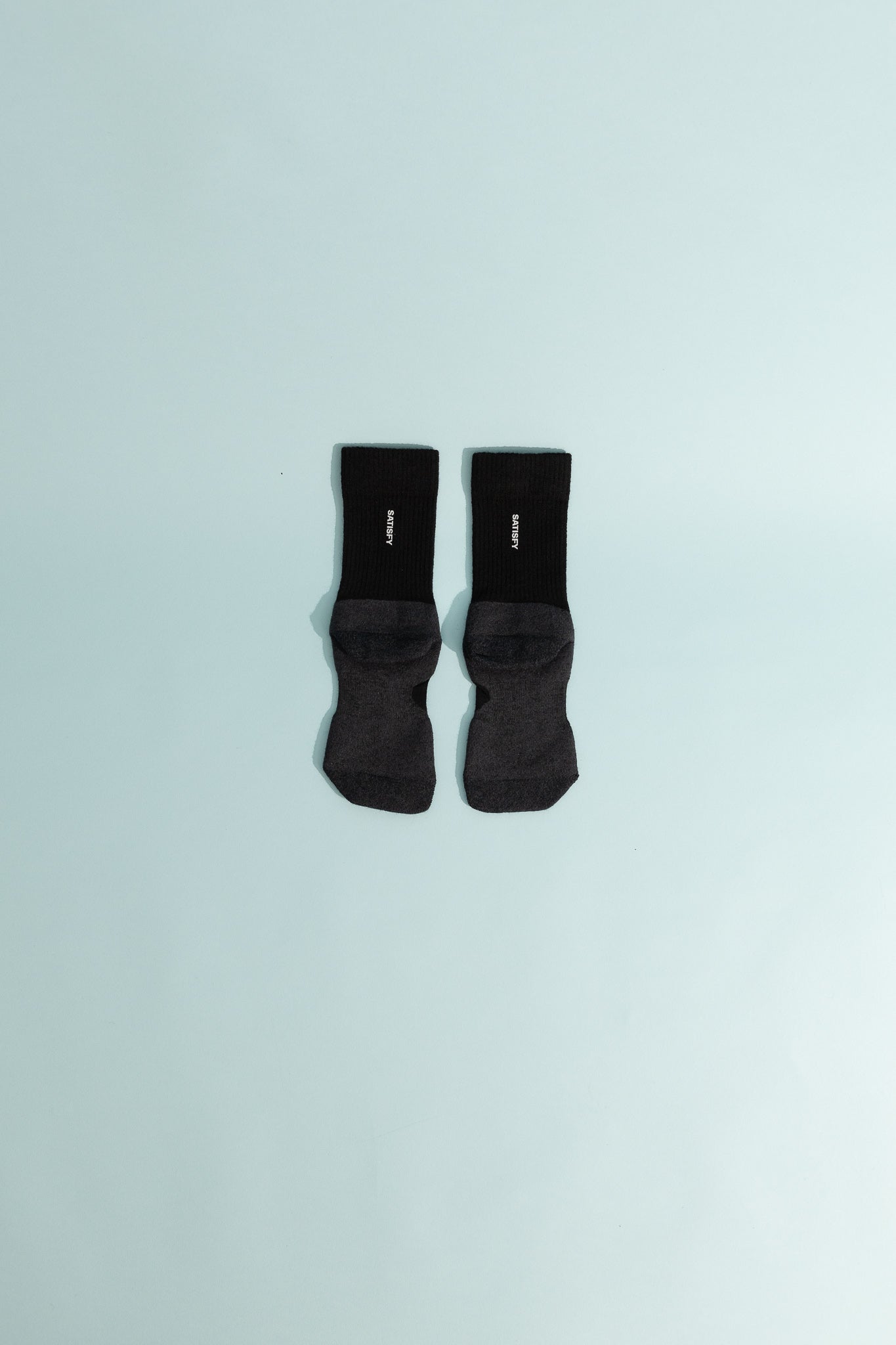 Merino Nylon Tube Socks - Black displayed on a light blue background showing their cushioning and support features.