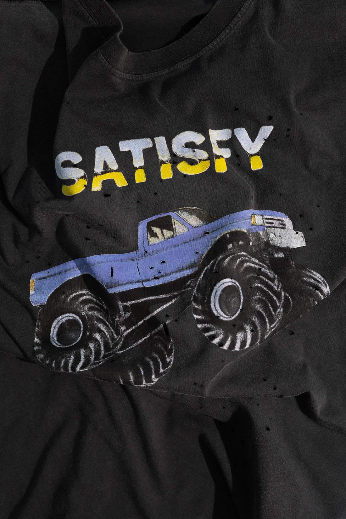 MothTech™ T-Shirt design featuring a blue monster truck and the word 'SATISFY' on aged black fabric.